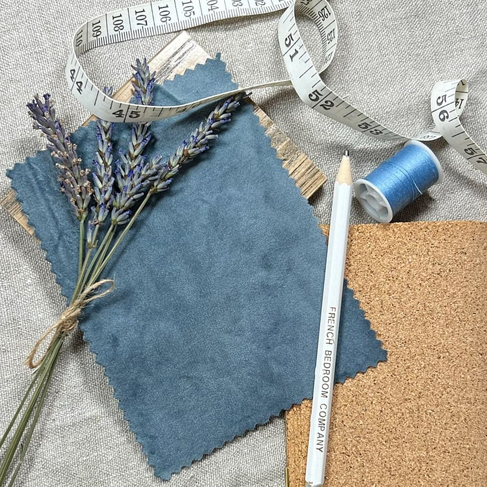 A blue fabric sample, presented with a sprig of lavendar and a dressers tape