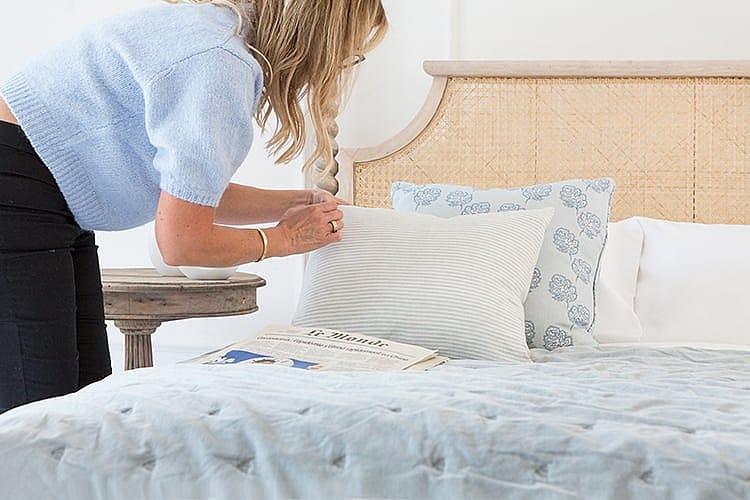 French Bedroom Founder, Georgia, styling a rattan bed with an array of blue and white soft furnishings