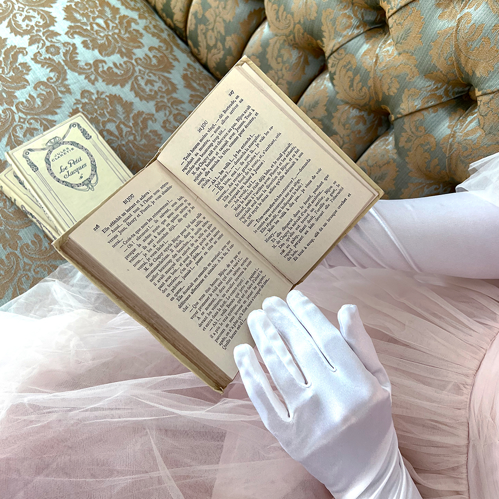Vintage book being read by woman with white regal gloves