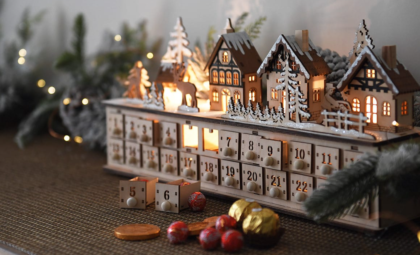 glowing wooden advent calendar with town scene and open drawers