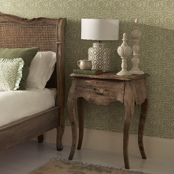 a single drawer, wooden bedside table, with a pair of finials and a lamp on top. 