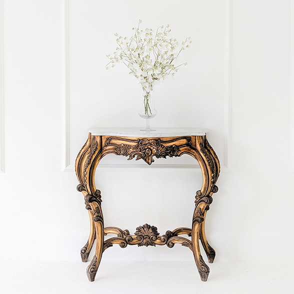 Gold, ornate console table with a marble top. 